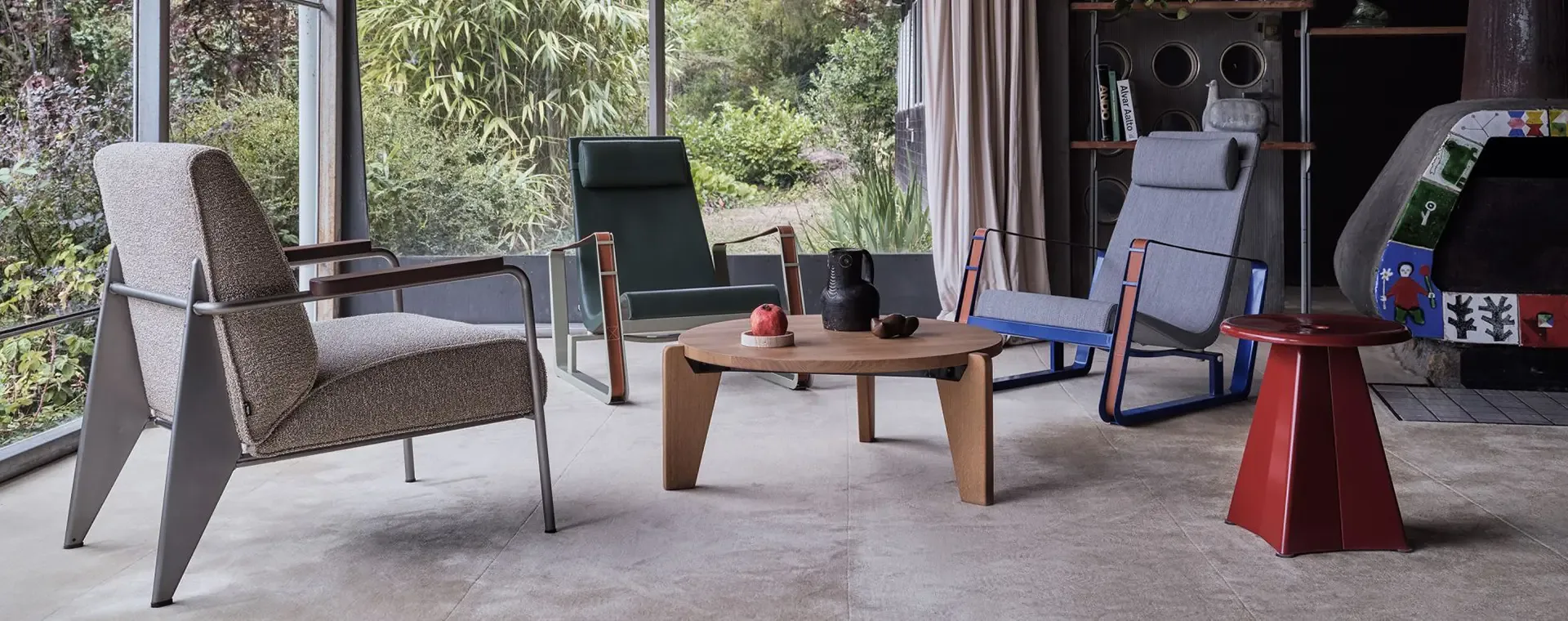 Wohnraum mit Sesseln und Couchtisch von Vitra vor einer großen Fensterfront mit Blick ins Grüne