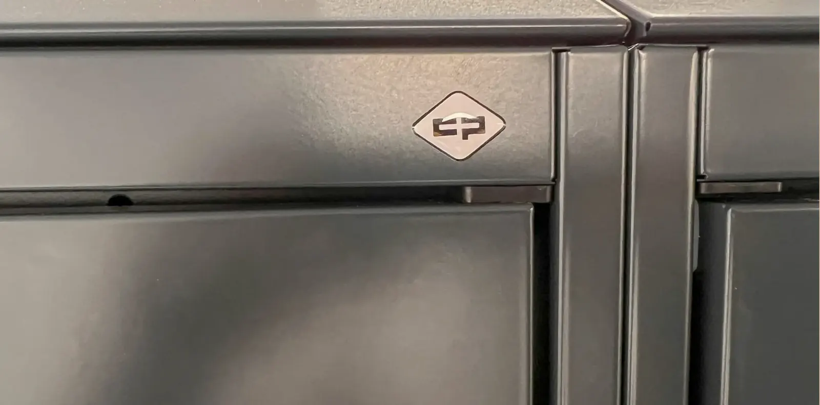 Nahaufnahme einer anthrazitfarbenen Spindtür aus Metall mit dem C+P-Logo auf der Oberkante.